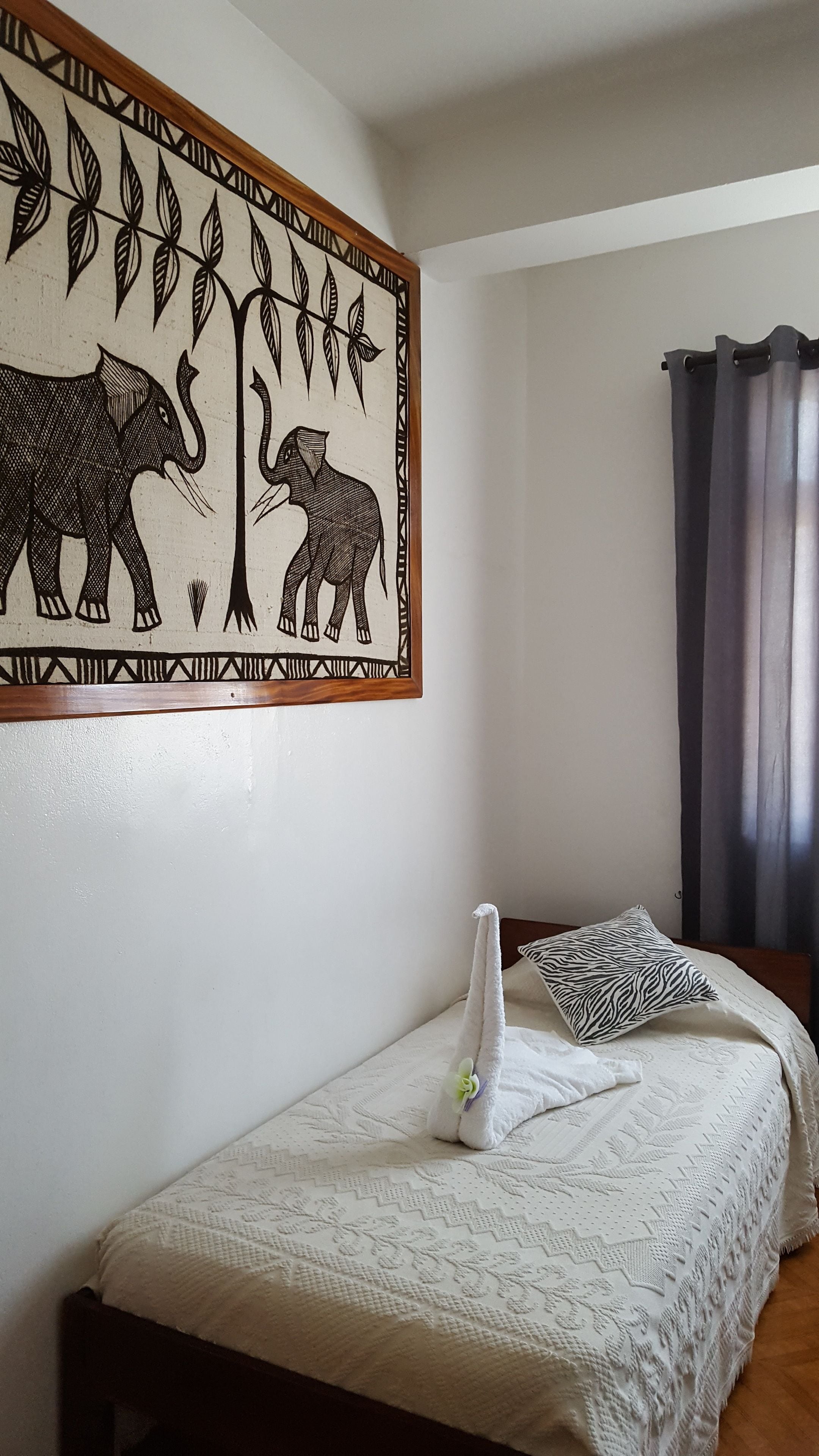 Une chambre à coucher avec un lit, une décoration murale, un coussin et un rideau.