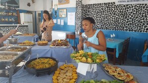 Ein reichhaltiges Buffet mit verschiedenen Speisen und einer blau-weißen karierten Tischdecke.