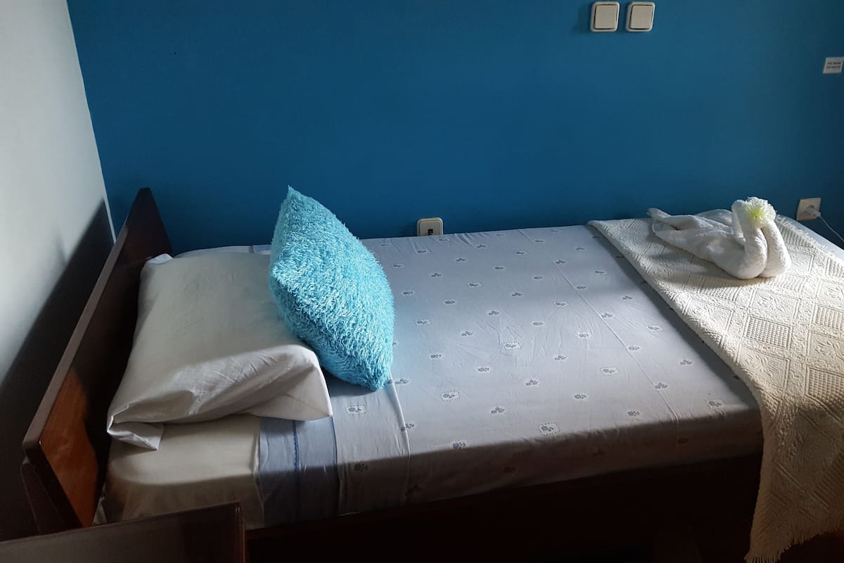 A single bed with a patterned mattress, a blue pillow, and a white towel.