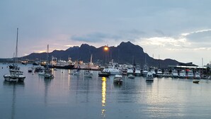 Ein Yachthafen mit anlegenden Booten, ein Berg im Hintergrund und ein Gebäude mit einem Schild.