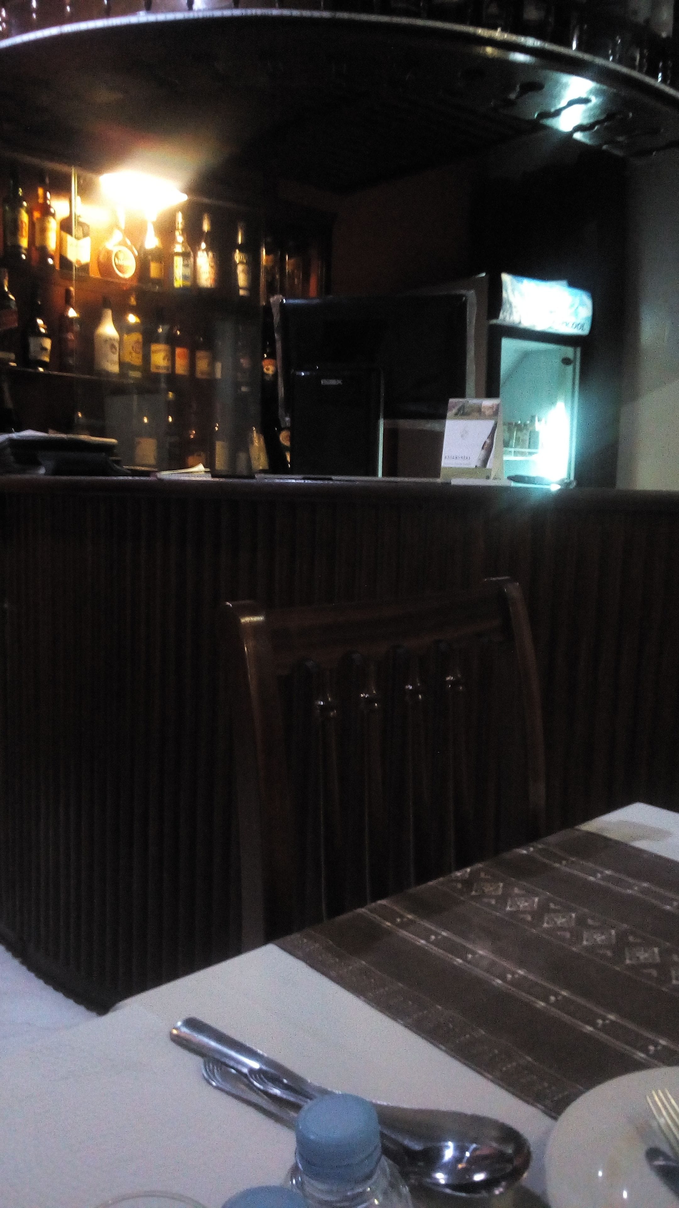 A restaurant interior with a bar area, wooden booths, and a table set with cutlery.