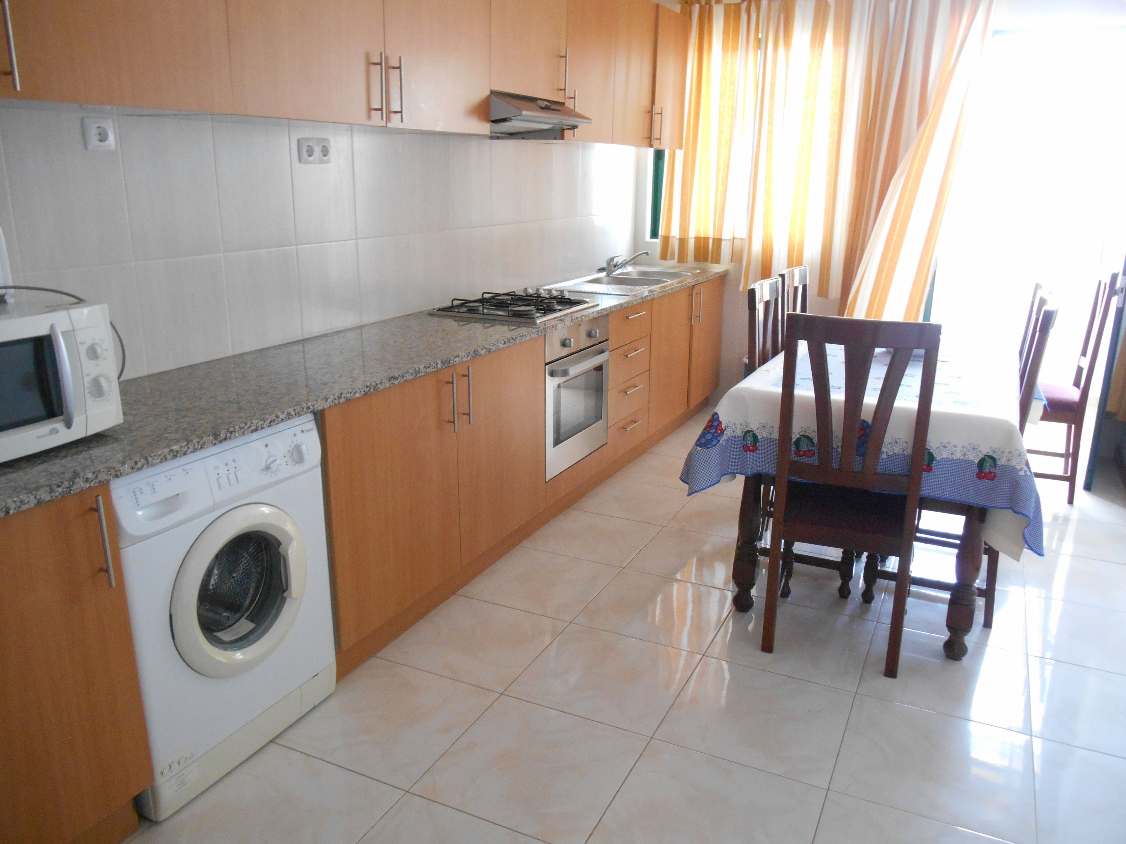 A kitchen with a washing machine, microwave, stove, and oven.