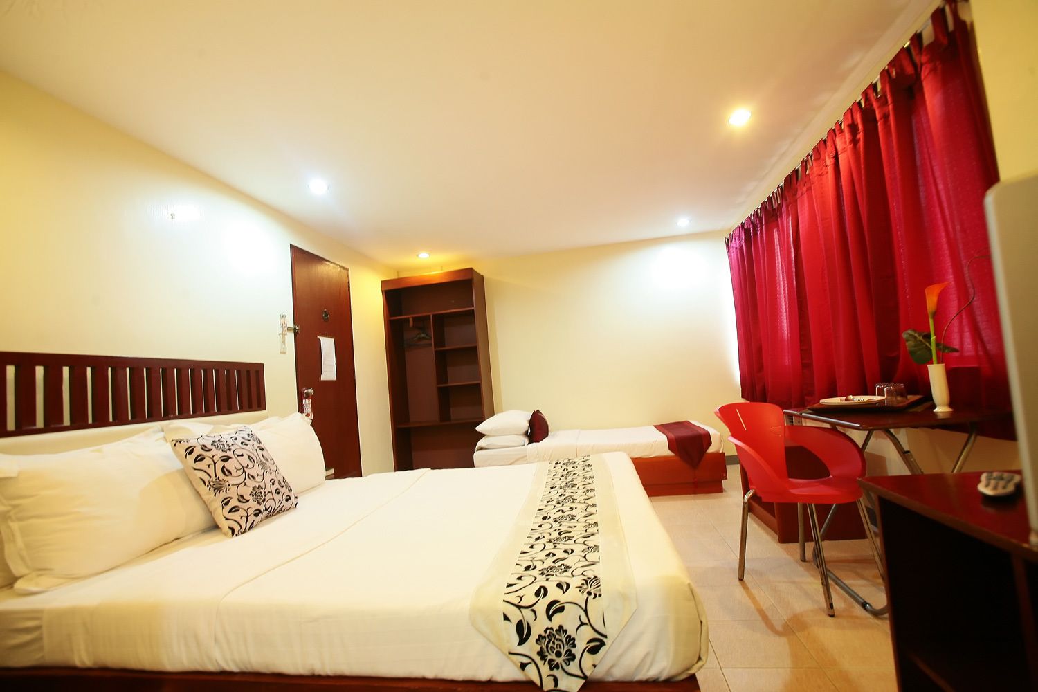 A hotel room with a large bed, a desk, a chair, and a wardrobe.