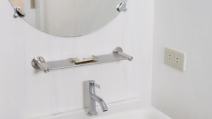 Un baño con un lavabo blanco, un espejo redondo y un perchero para toallas.