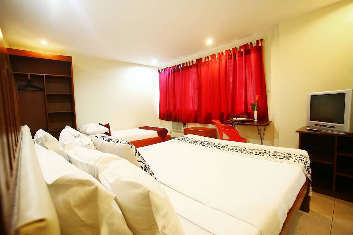 A hotel room with two beds, a desk, a TV, and a wardrobe.