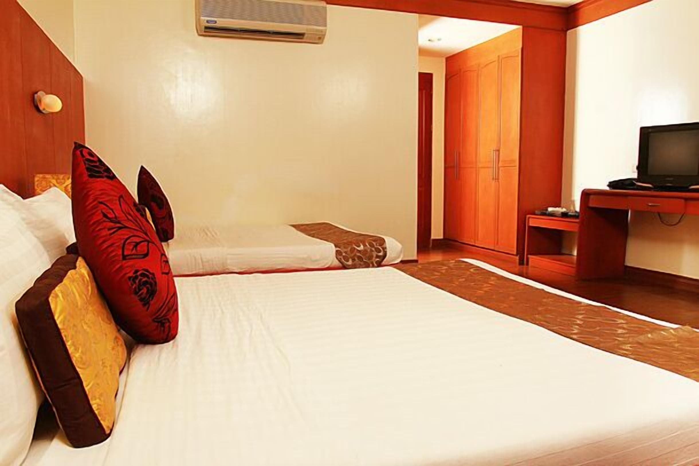 A hotel room with a bed, a television, and a wardrobe.