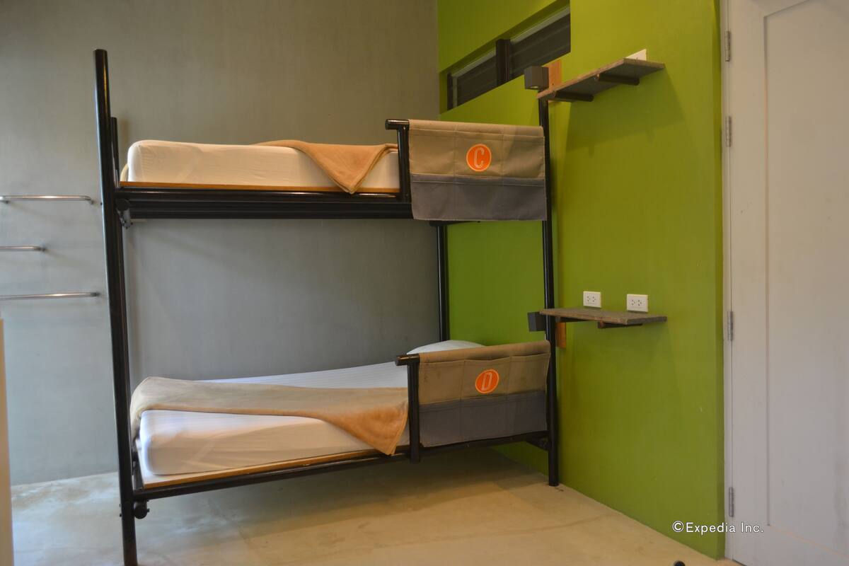 A bunk bed with storage drawers and a shelf, against a green wall with a white door.