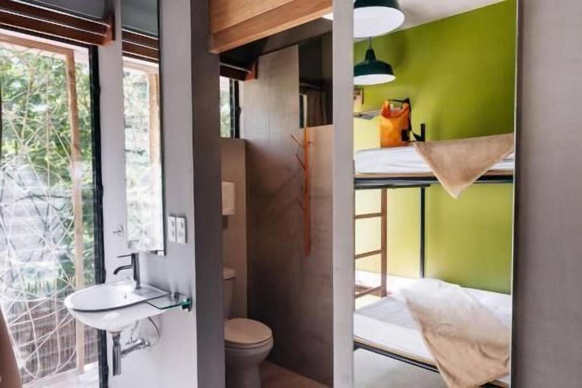 A compact room with a toilet, sink, and bunk bed.