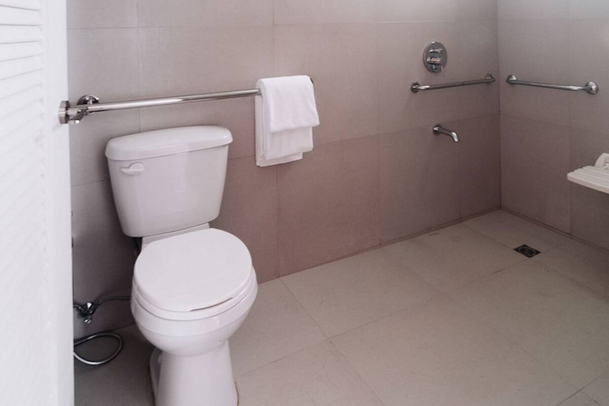 A modern bathroom with a toilet, a towel rack, a shower area, and a ceiling light fixture.