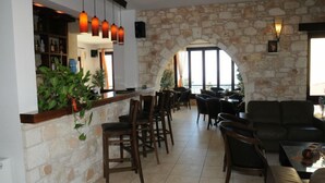 A spacious indoor area with a stone wall, a bar counter, and several seating arrangements including chairs and a sofa. - Palates Village Hotel (Droushia)