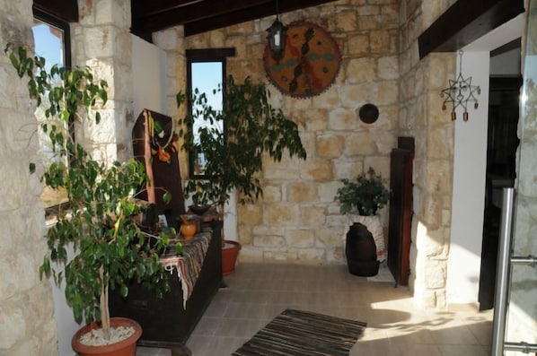 A stone-walled interior with potted plants, a hanging lantern, and a rustic wooden bench.