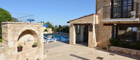 A stone building with a swimming pool, a stone archway, and a balcony.