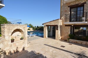 A stone building with a swimming pool, a stone archway, and a balcony.