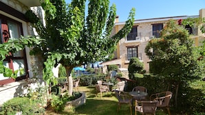 A courtyard with a stone building, a tree, and outdoor furniture. - Palates Village Hotel (Droushia)