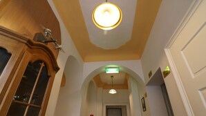 A hallway with a wooden cabinet, an exit sign, and a fire extinguisher. - Pension Alt-Strassgang (Graz)