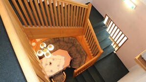 A corner seating area with a table and chairs, a wooden railing, and a staircase. - Pension Alt-Strassgang (Graz)