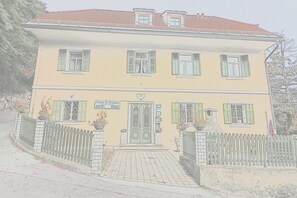 A two-story building with a yellow facade, green shutters, and a brick entrance. - Pension Alt-Strassgang (Graz)
