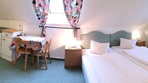 A small, compact room with a single bed, a desk with a chair, a small kitchenette, and a window with curtains. - Pension Alt-Strassgang (Graz)