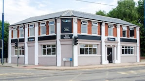 A two-story building with a flat roof, multiple windows, and a sign that reads "Trivelles." - Trivelles Hotels - Eccles New Road (Salford)