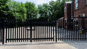 A gated area with a brick building, trees, and a clear sky. - Trivelles Hotels - Eccles New Road (Salford)