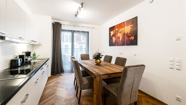 Cocina moderna con comedor, que incluye una mesa y sillas de madera, una cafetera y vistas al exterior.