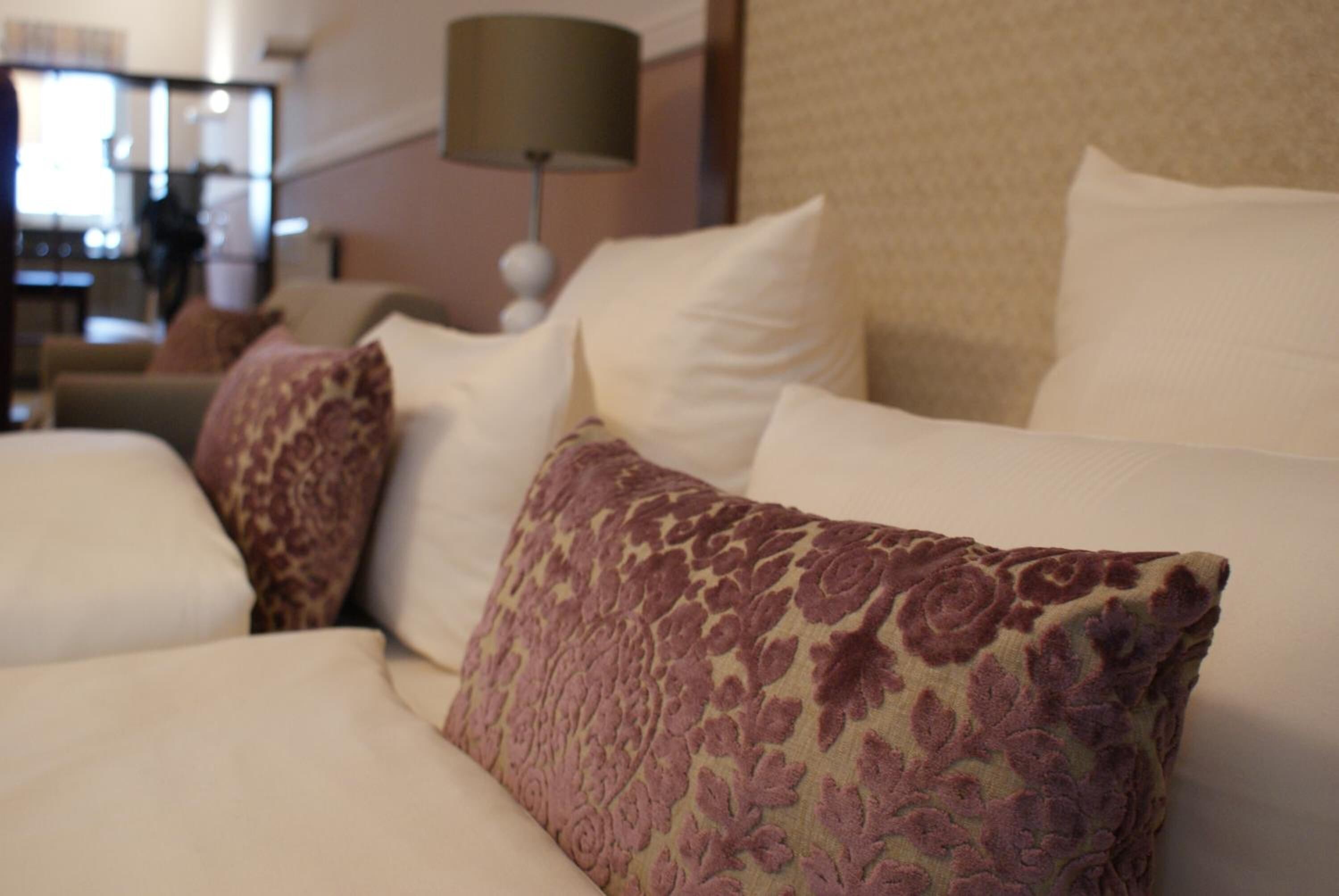 Ein Hotelzimmer mit einem Bett, Kissen und einer Lampe.