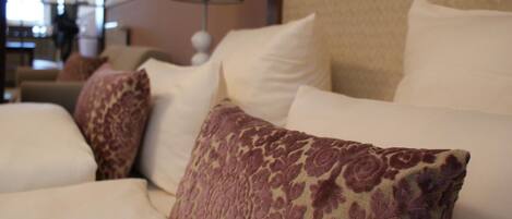 A hotel room with a bed, pillows, and a lamp.