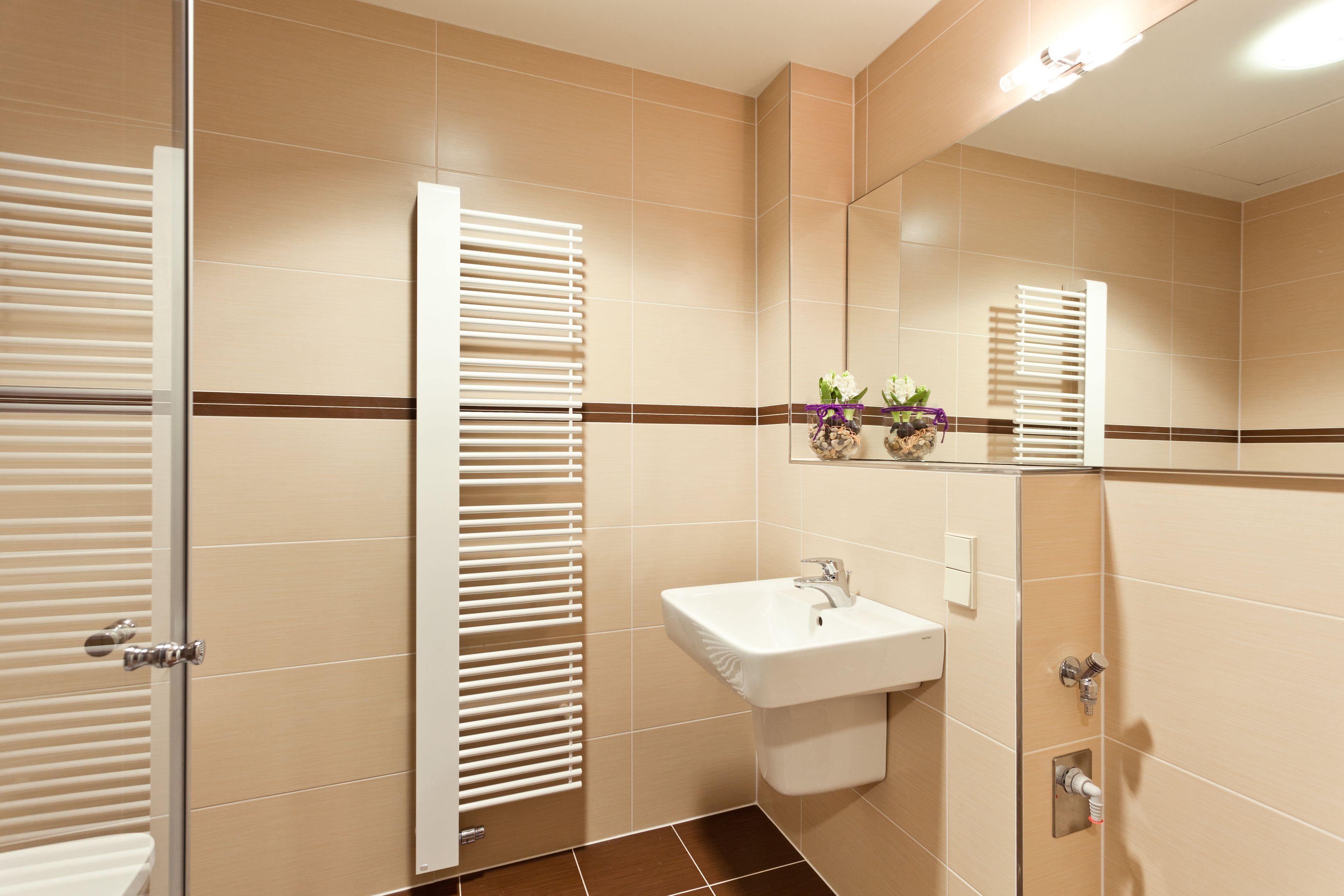 Een badkamer met een wit wastafel, een spiegel en een douche.