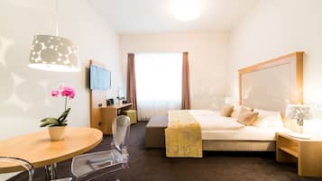 Une chambre d’hôtel comprenant un lit, une table de chevet, une lampe, une chaise, un bureau et une plante en pot.