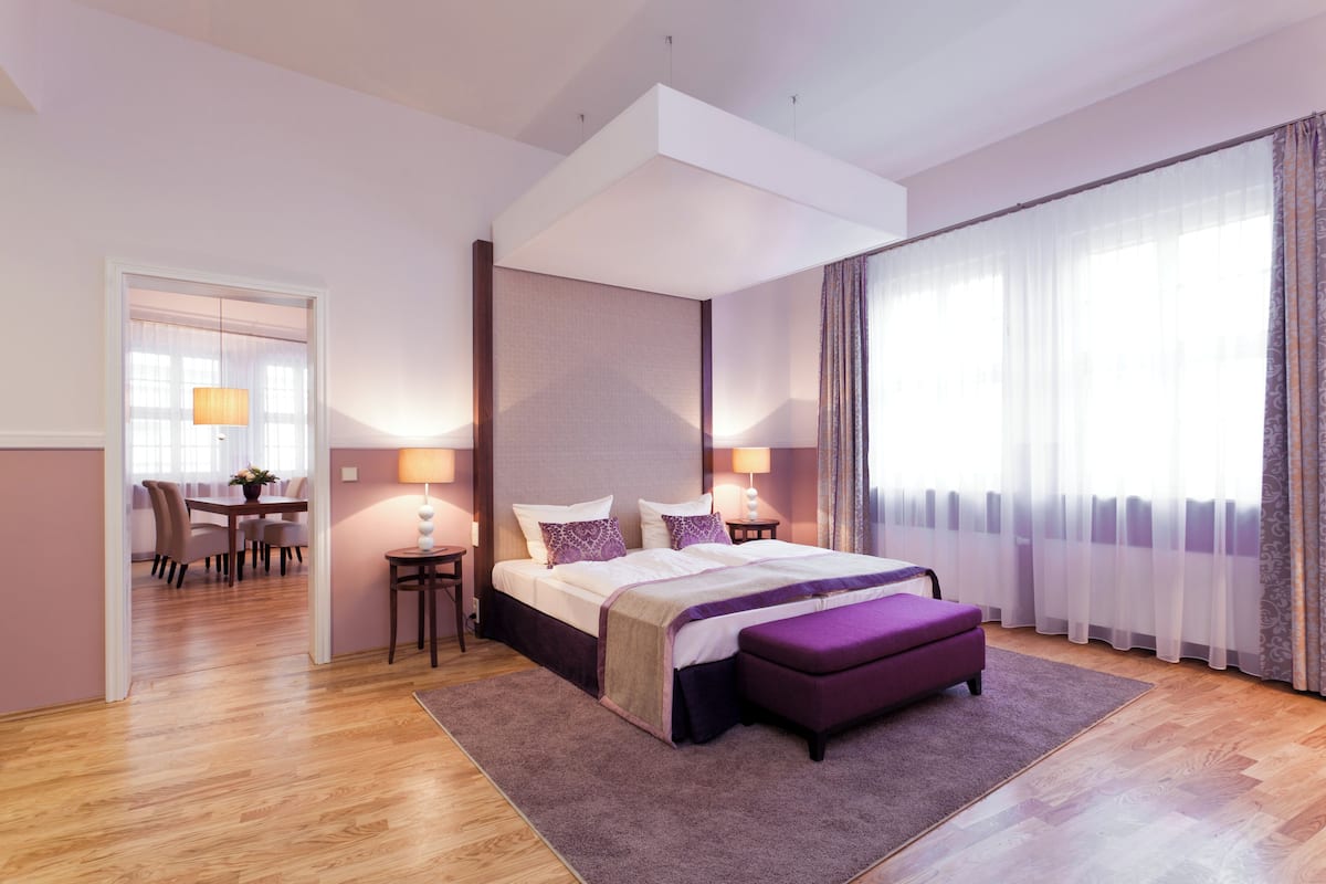 Ein modernes Hotelzimmer mit einem großen Bett, einer Essecke und Blick auf die Stadt.