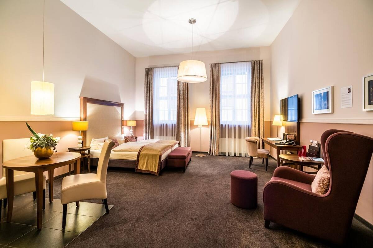 Ein Hotelzimmer mit Bett, Schreibtisch, Stuhl, Tisch und einer Couch.