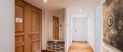 A hallway with wooden flooring, a bench with storage compartments, and a large abstract painting on the wall.