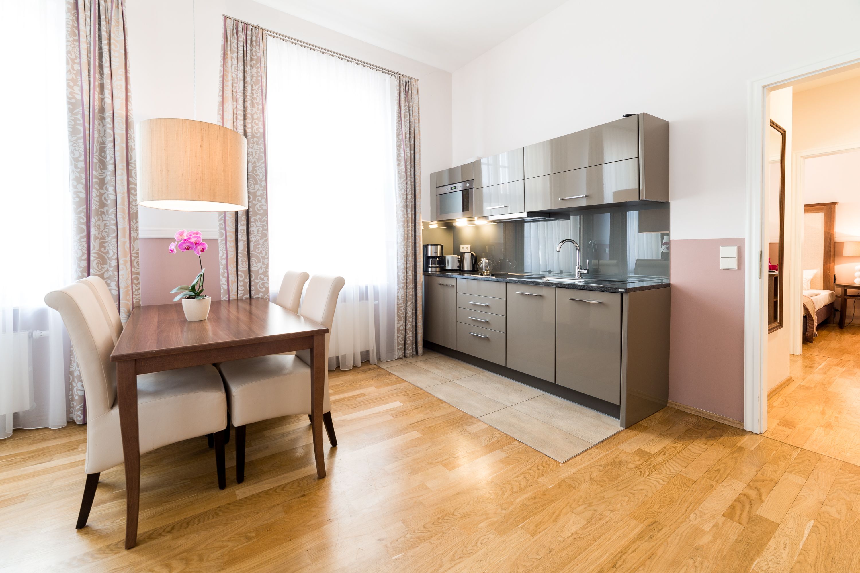 Una cocina moderna con armarios grises, una mesa de comedor de madera y una orquídea en maceta.