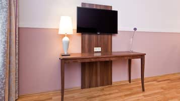 Una mesa de madera con una lámpara y un televisor de pantalla plana montado en la pared.