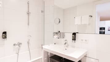 A modern bathroom with a white sink, a glass shower enclosure, and a hand wash station.