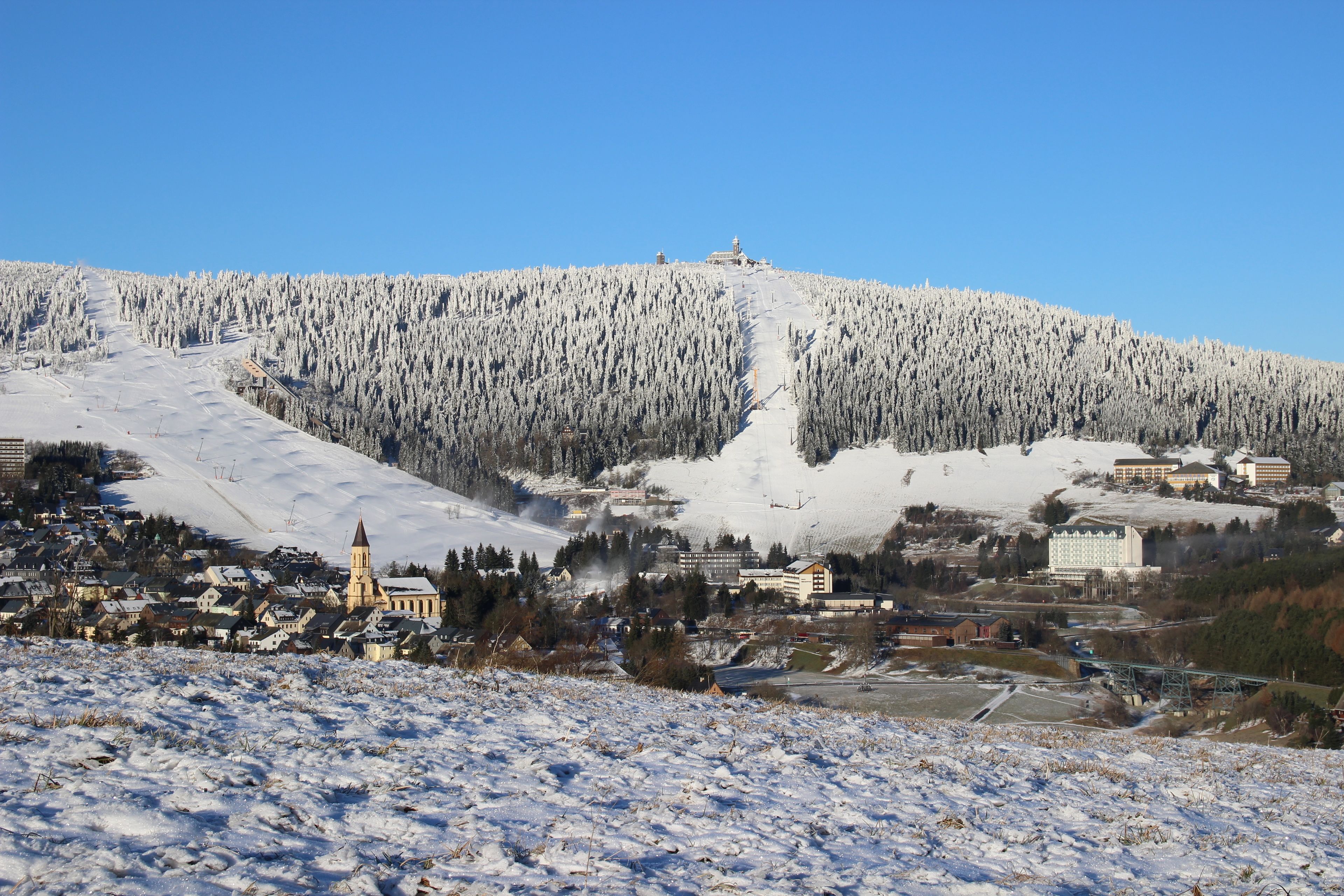 A snow-covered mountain with a ski resort, buildings, and a church.