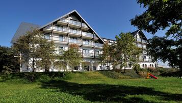 Hotel surrounded by lush greenery and a playground, offering a tranquil atmosphere.