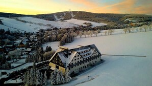 Ein verschneites Dorf mit traditionellen Häusern, einer markanten Kirche und einer Erhebung im Hintergrund.