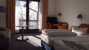 A hotel room with two beds, a desk, a chair, and a window with curtains.