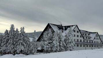A large, multi-story building with a symmetrical roofline, surrounded by snow-covered trees.