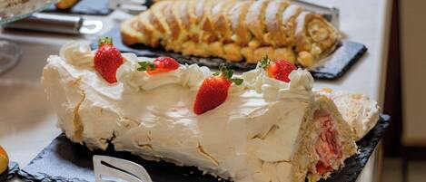 A dessert table with a meringue-topped cake, a braided pastry, and a variety of other baked goods.