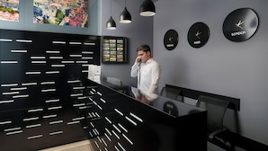 En moderne receptionsdisk med en sort overflade og hvide linjer, tre sorte hængende lamper og ure, der viser tiden for Paris og London.