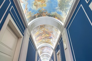 Stunning fresco-adorned corridor with a high ceiling and classical architectural details.