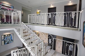 A multi-level interior with white metal railings, a staircase, and artwork on the walls.