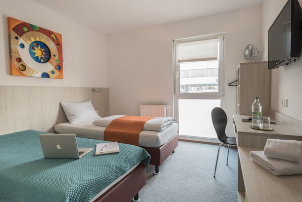 A modern hotel room with a bed, desk, and laptop. - Motel Einstein Erding (Erding)