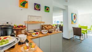 Un buffet pour le petit-déjeuner proposant divers aliments et un saladier rempli de fruits.