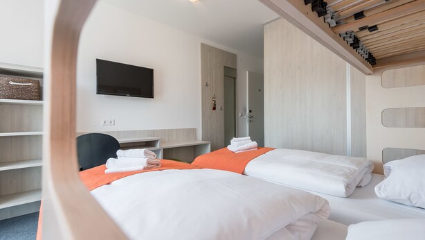 Une chambre d’hôtel avec deux lits, un téléviseur à écran plat, un bureau et une armoire.