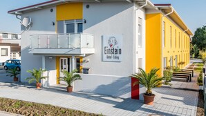 Un bâtiment à deux étages avec une façade jaune et blanche, un balcon et une enseigne indiquant « Einstein Motel Erding ».
