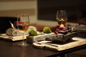 A dining table with two wine glasses, a fork, a knife, and a dessert plate with fruits and a cake. - Atrium Hotel (Vysoké Tatry)
