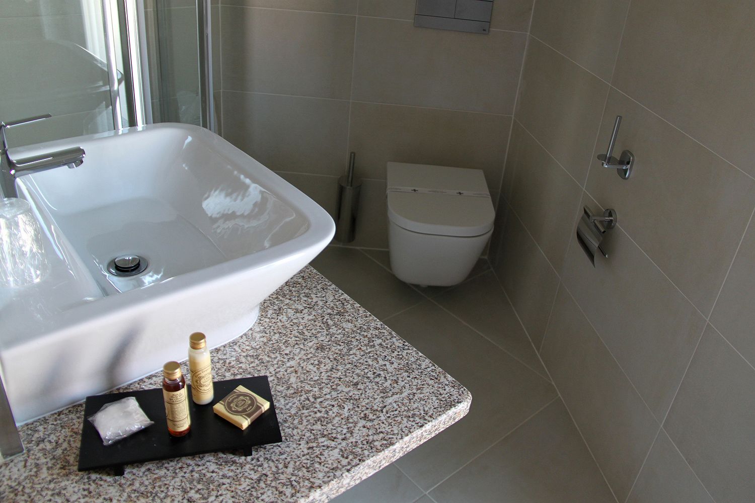 A bathroom with a white sink, a toilet, and a granite countertop.